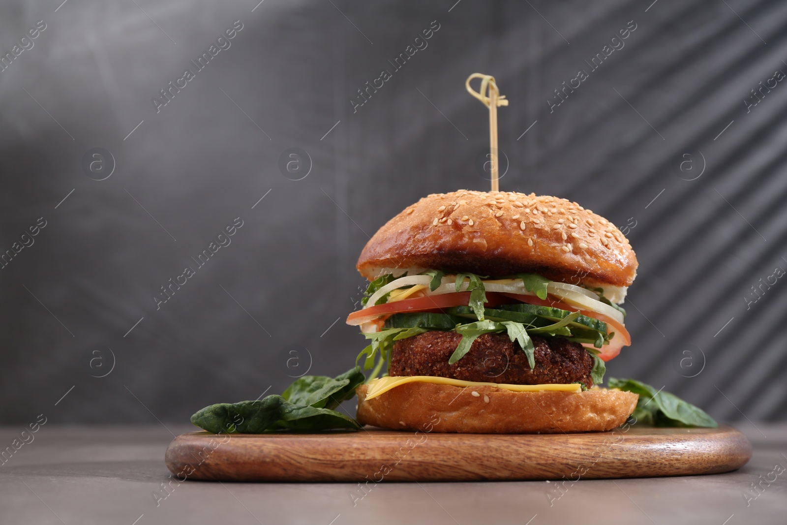 Photo of Board with delicious vegetarian burger on grey table. Space for text