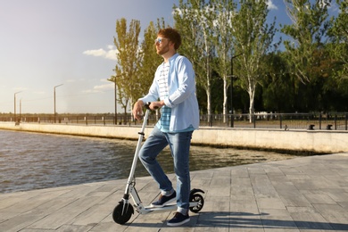 Man with modern kick scooter on waterfront
