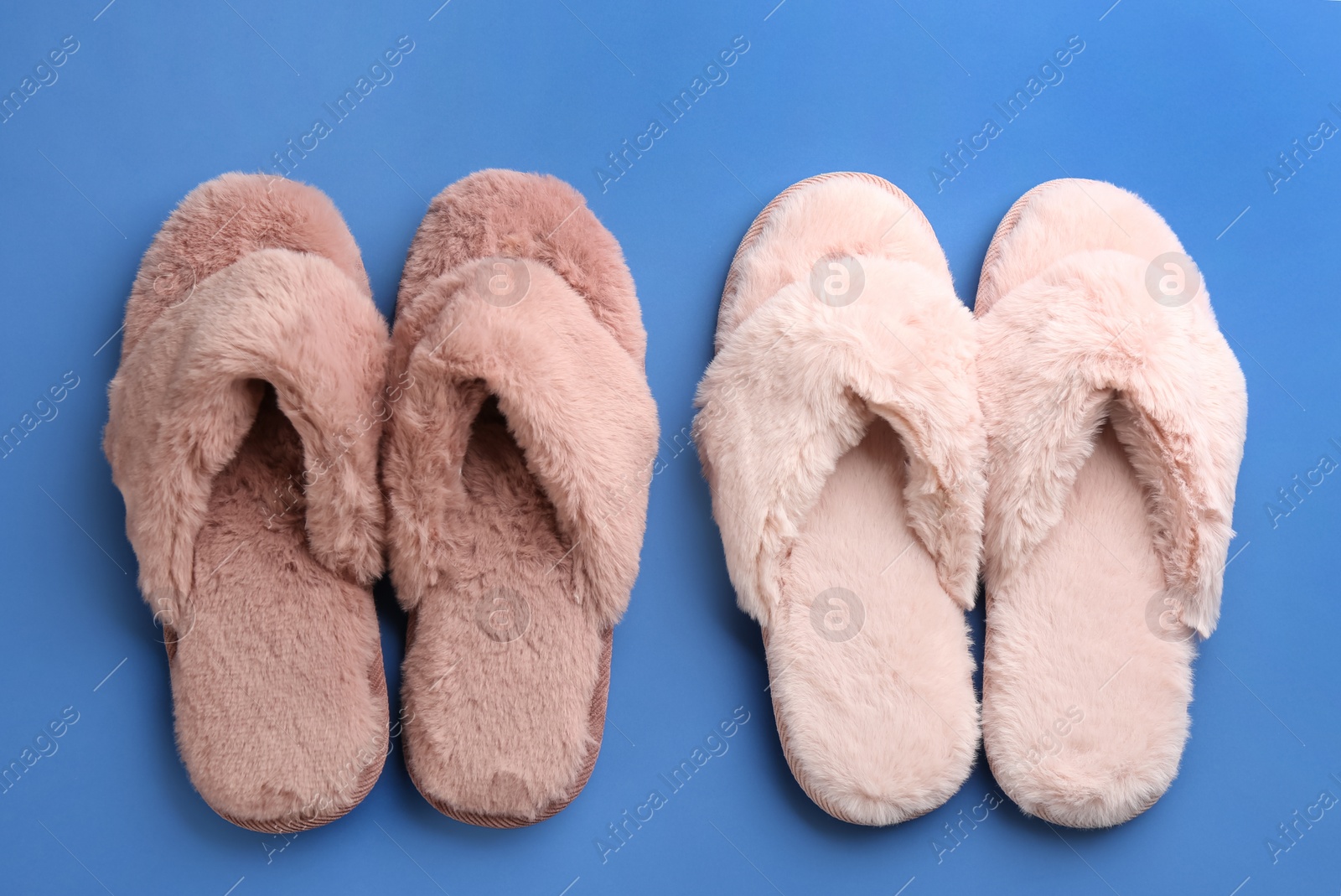 Photo of Different stylish soft slippers on blue background, flat lay