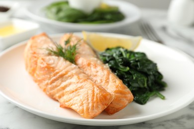 Photo of Tasty salmon with spinach and lemon on table