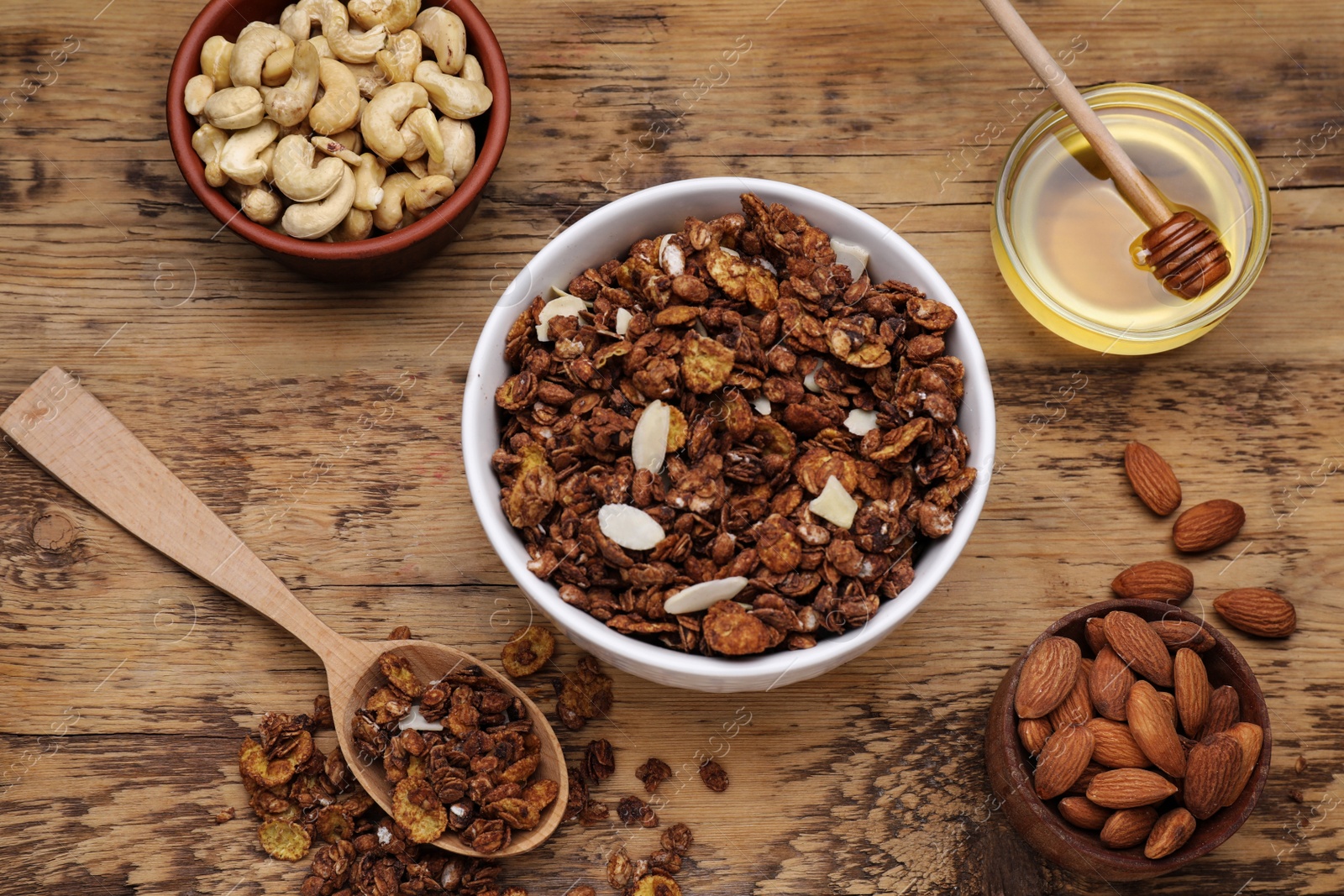 Photo of Tasty granola served with nuts and dry fruits on wooden table, flat lay