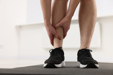 Photo of Man suffering from leg pain on mat indoors, closeup. Space for text