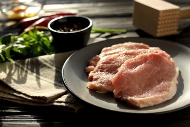 Cooking schnitzel. Plate with raw pork slices on black wooden table, closeup