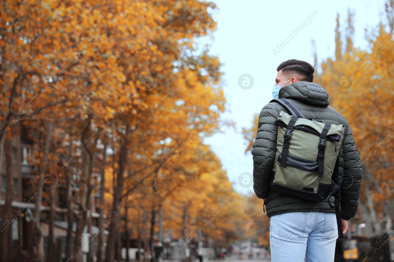 Photo of Male tourist with travel backpack on city street, back view. Urban trip