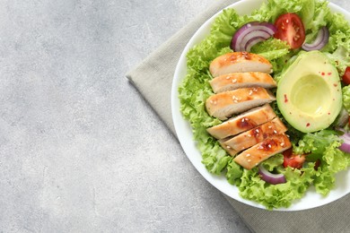 Photo of Delicious salad with chicken, avocado and vegetables on light grey table, top view. Space for text
