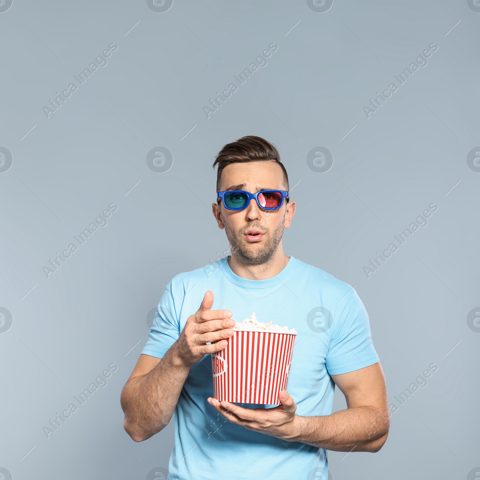 Photo of Emotional man with 3D glasses and popcorn during cinema show on grey background