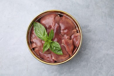 Photo of Bowl with raw chicken liver and basil on light grey table, top view