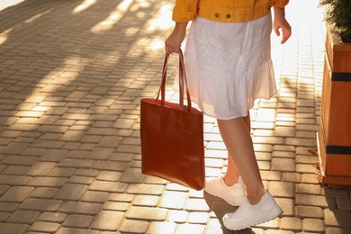 Photo of Woman with stylish shopper bag outdoors, closeup. Space for text