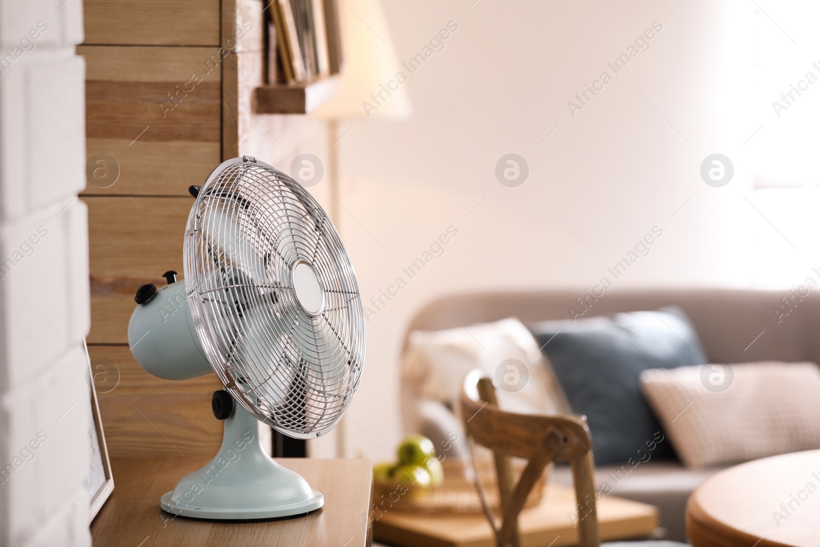 Photo of Modern electric fan on wooden table in living room. Space for text