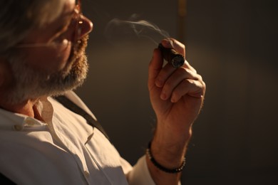 Photo of Bearded man smoking cigar on dark background, closeup