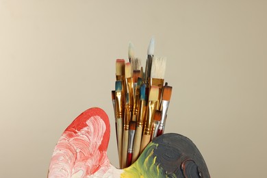 Photo of Many paintbrushes and palette on beige background