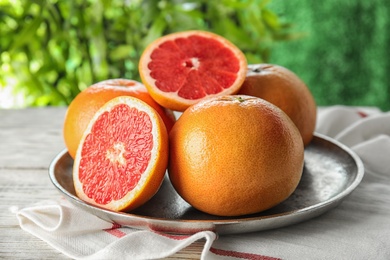 Photo of Plate of grapefruits on table against blurred background