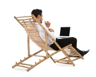Young businessman with laptop on sun lounger against white background. Beach accessory