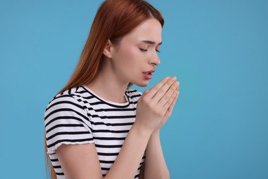 Woman coughing on light blue background, space for text. Cold symptoms
