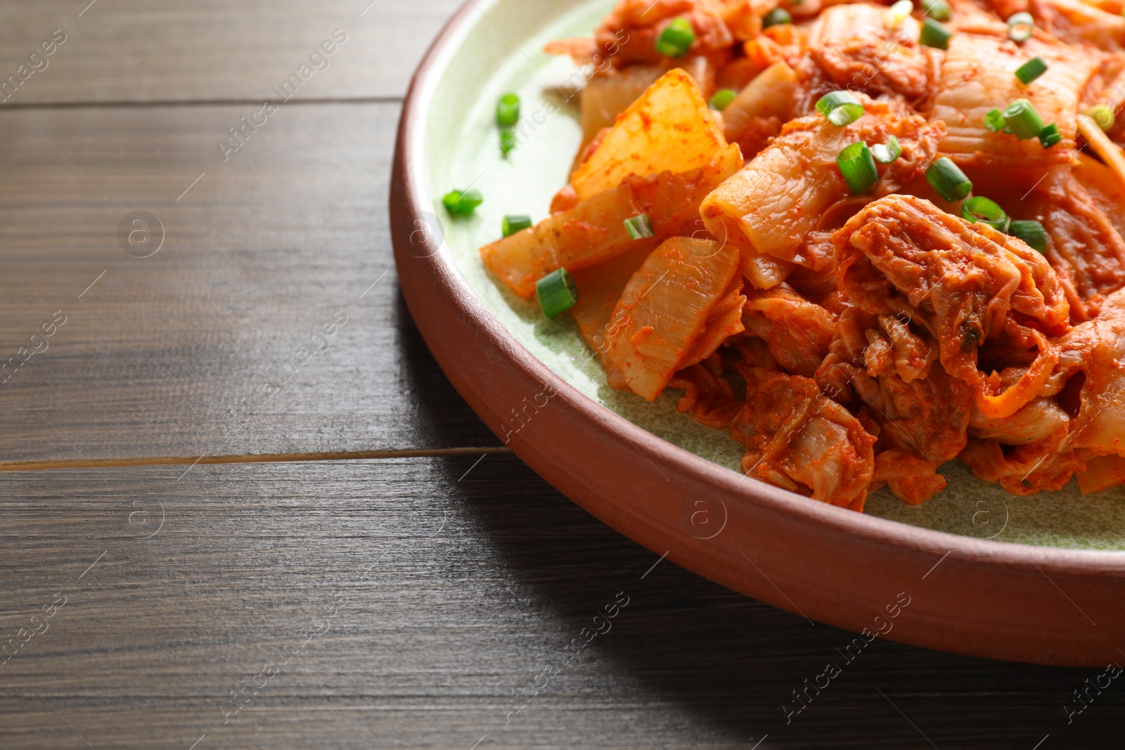 Photo of Plate of delicious kimchi with Chinese cabbage on wooden table, closeup. Space for text