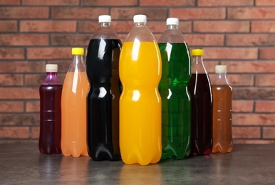 Photo of Bottles of soft drinks on table near brick wall