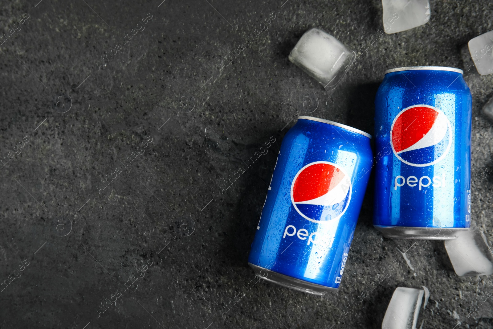Photo of MYKOLAIV, UKRAINE - FEBRUARY 11, 2021: Cans of Pepsi with water drops and ice cubes on grey table, flat lay. Space for text