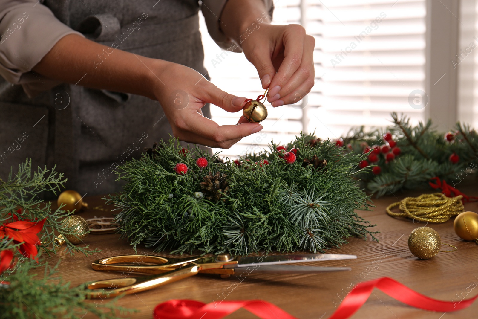 Photo of Florist making beautiful Christmas wreath at wooden table indoors, closeup