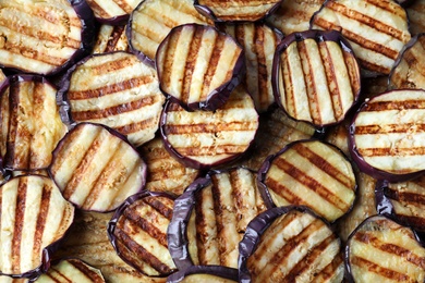Photo of Delicious grilled eggplant slices as background, closeup