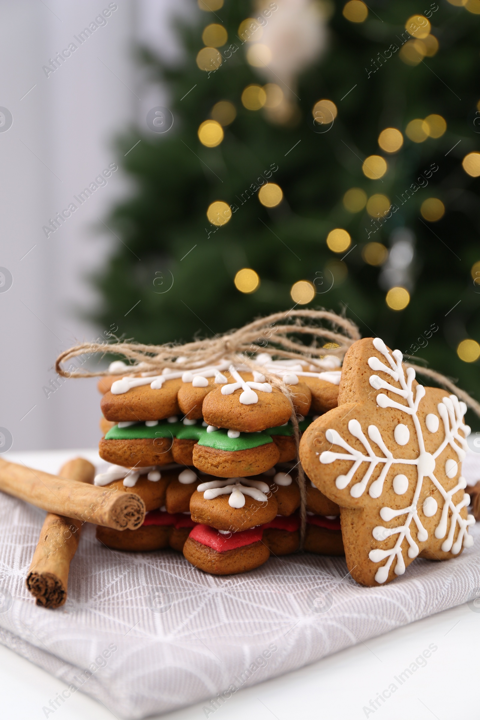 Photo of Decorated cookies on white table against blurred Christmas lights