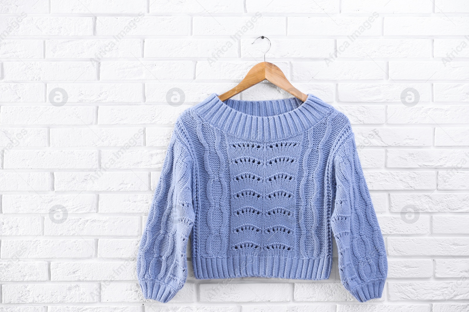 Photo of Hanger with stylish sweater on brick wall