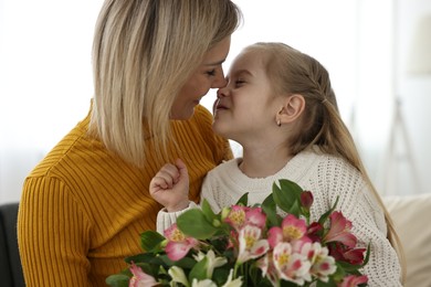 Photo of Little daughter congratulating her mom with bouquet of alstroemeria flowers at home. Happy Mother's Day
