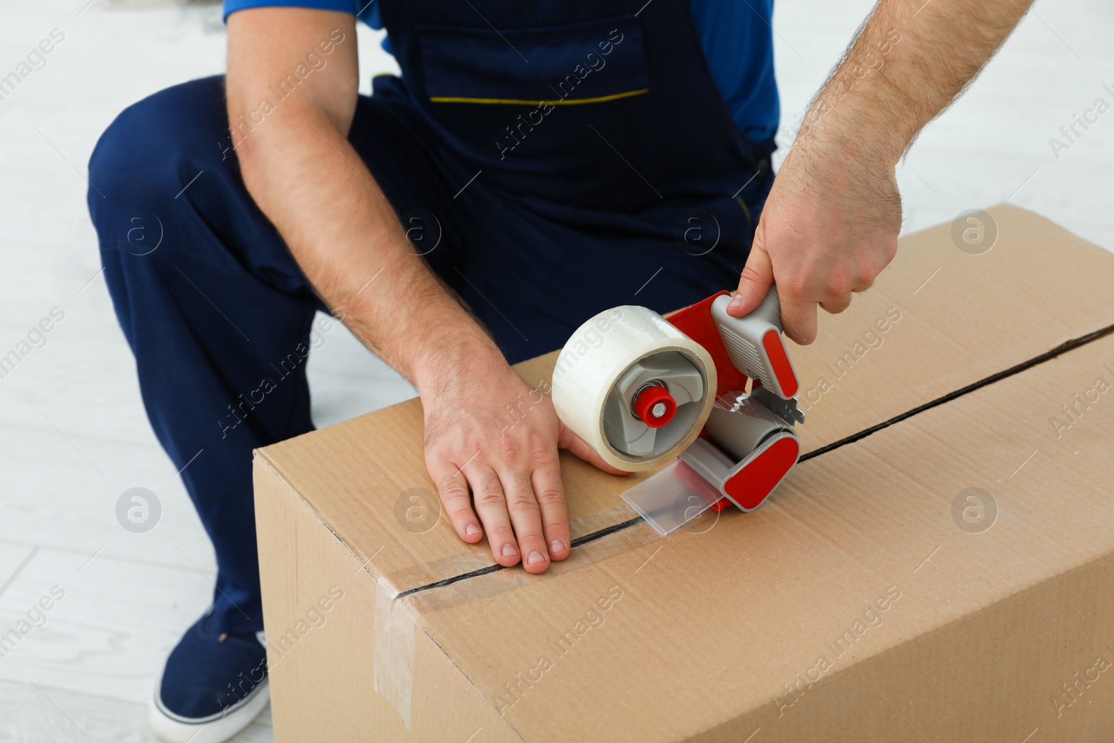 Photo of Young worker packing box in room, closeup. Moving service