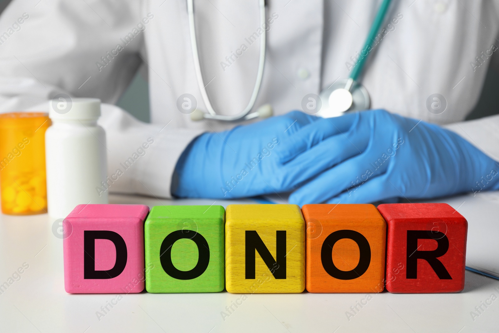 Photo of Word Donor made of wooden cubes. Doctor sitting at white table, closeup