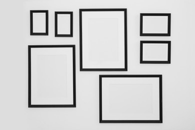 Different empty frames hanging on white wall