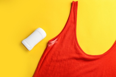 Clothes with stain and deodorant on yellow background, top view