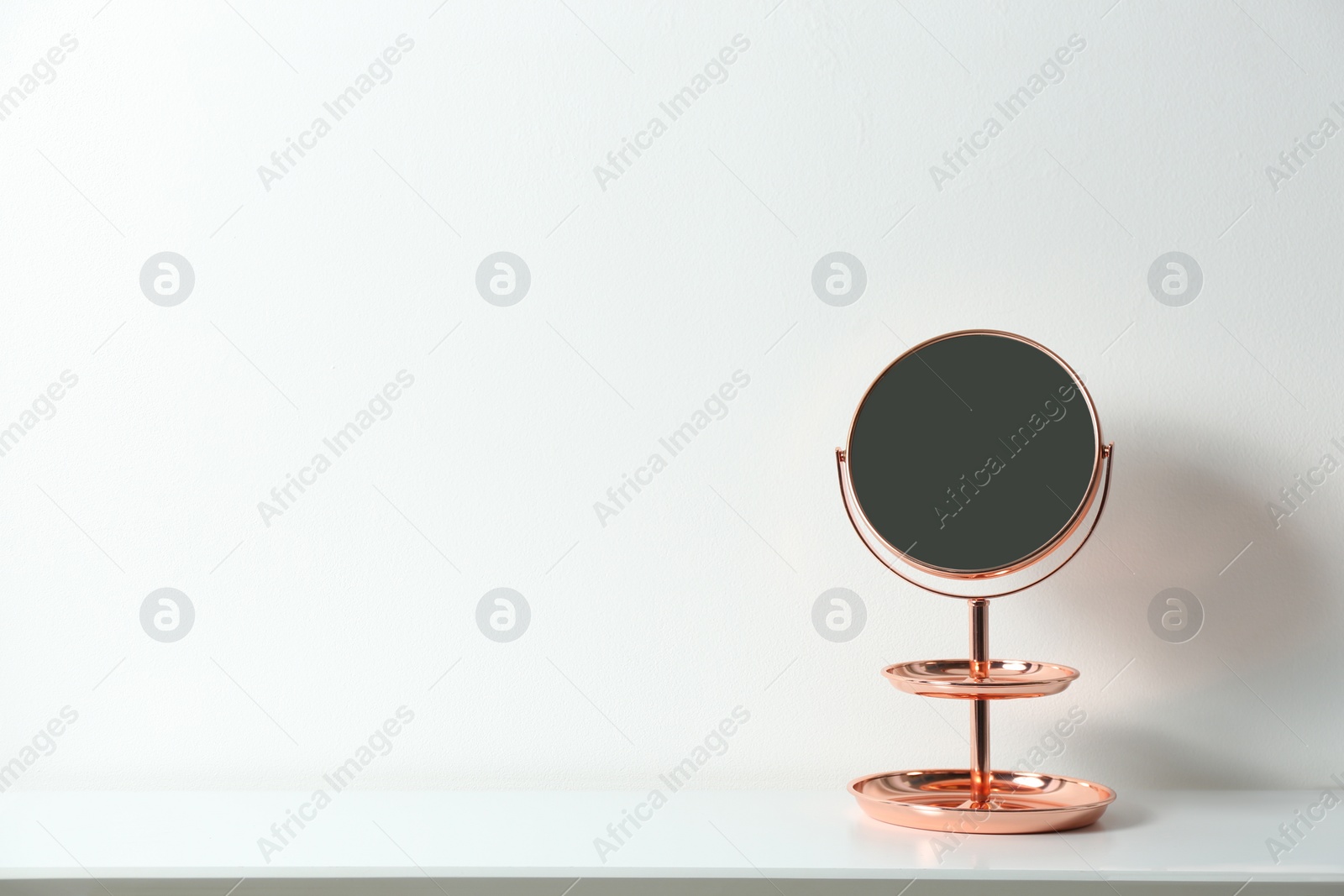 Photo of Small mirror on table near white wall. Space for text