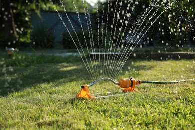 Automatic sprinkler watering green grass on lawn in garden. Irrigation system