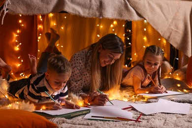 Photo of Mother and her children drawing in play tent at home