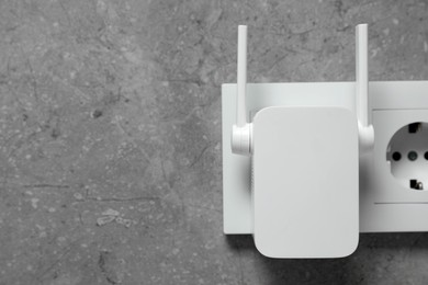 Photo of Wireless Wi-Fi repeater on light grey wall, space for text