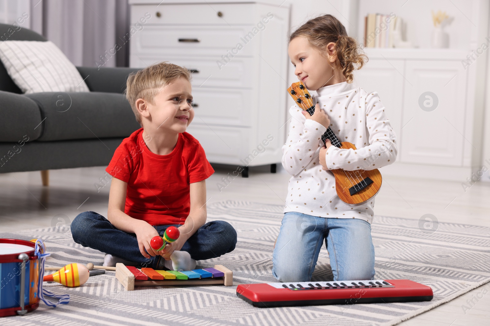 Photo of Little children playing toy musical instruments at home