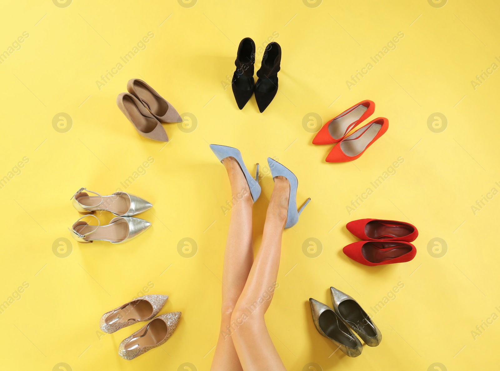 Photo of Woman and different high heel shoes on yellow background, top view