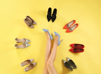 Photo of Woman and different high heel shoes on yellow background, top view