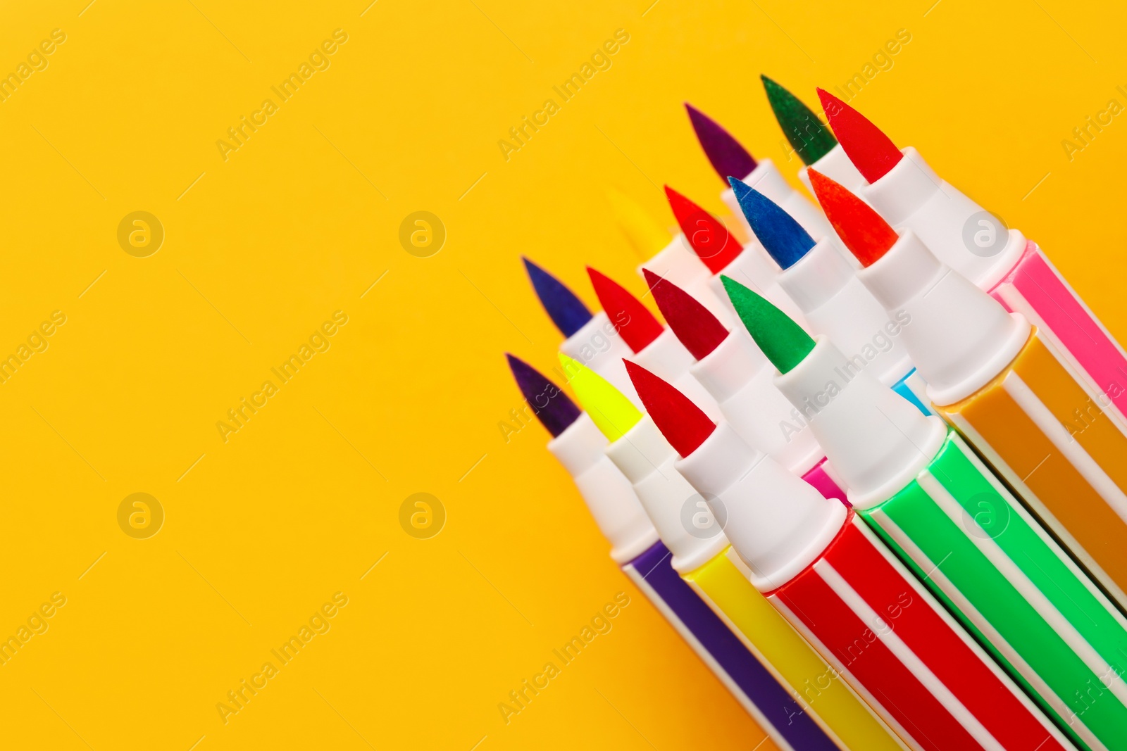 Photo of Many bright markers on yellow background, closeup. Space for text