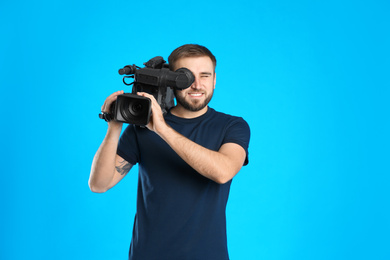 Operator with professional video camera on blue background