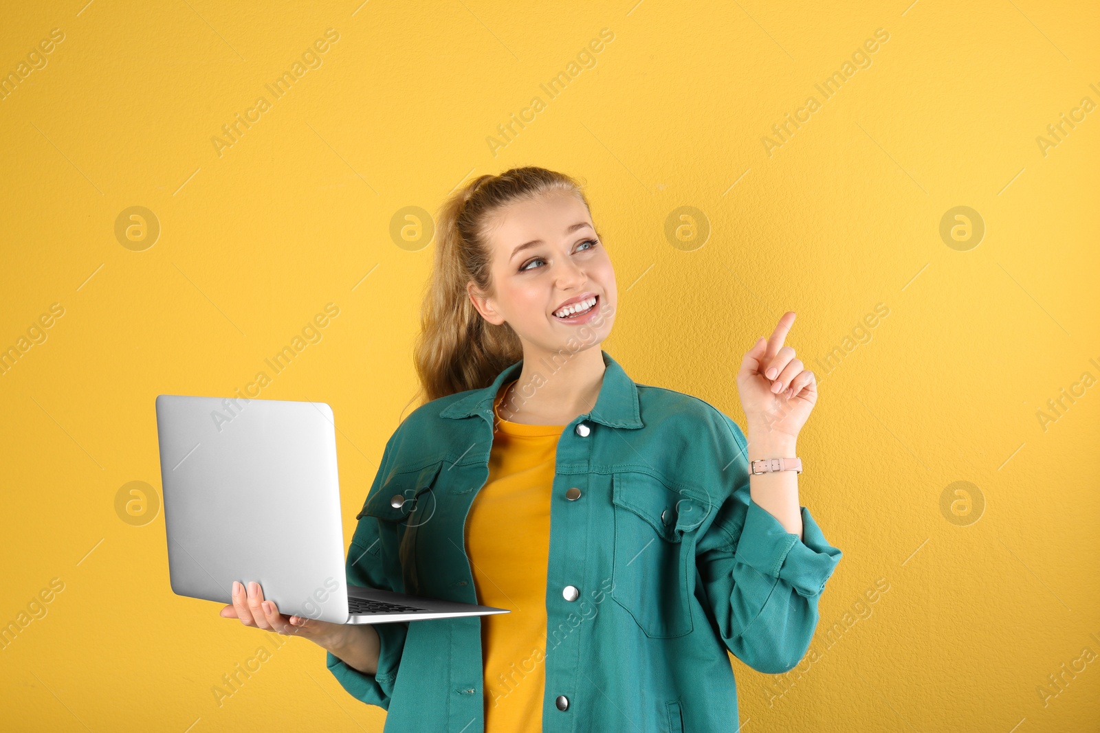 Photo of Portrait of beautiful young woman with laptop on yellow background