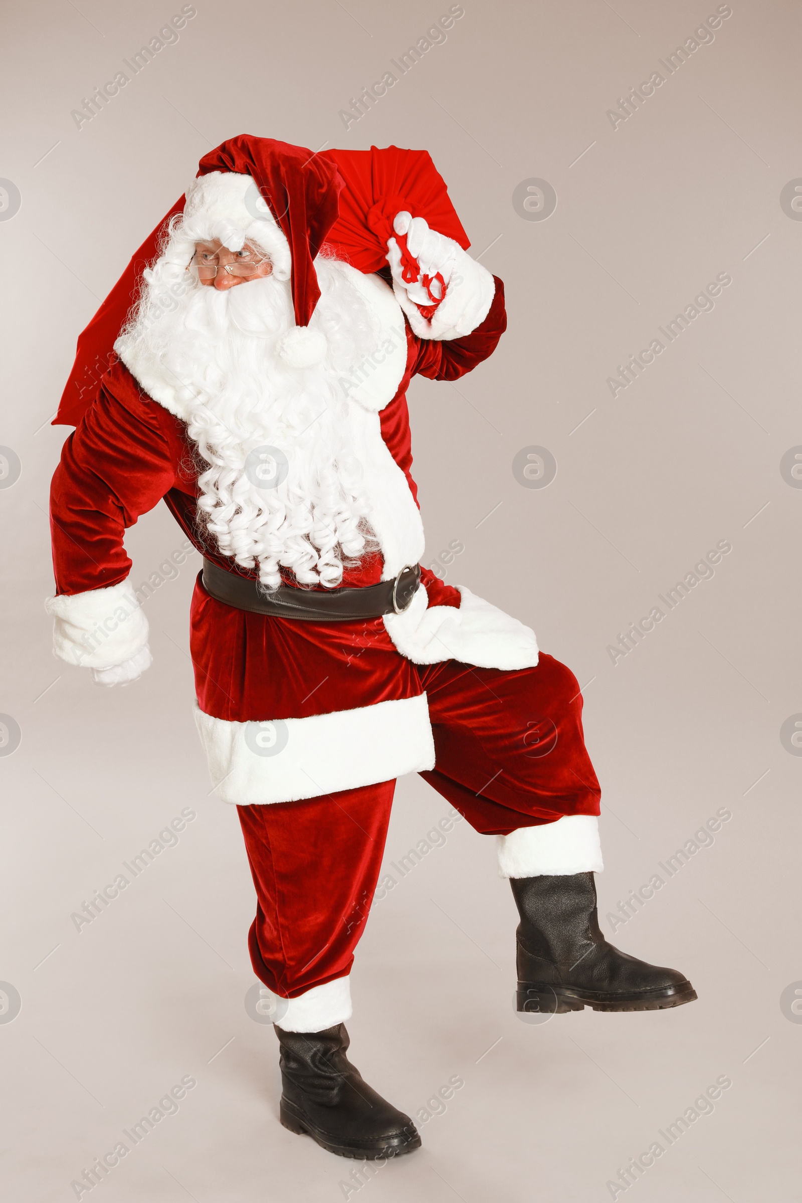 Photo of Authentic Santa Claus with bag full of gifts on grey background