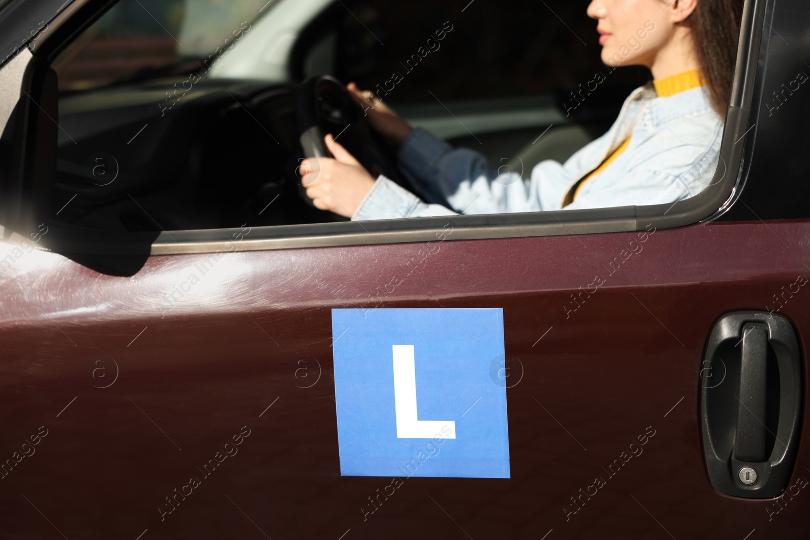 Photo of Learner driver driving car with L-plate, view from outside. Driving school