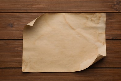 Photo of Sheet of old parchment paper on wooden table, top view. Space for design