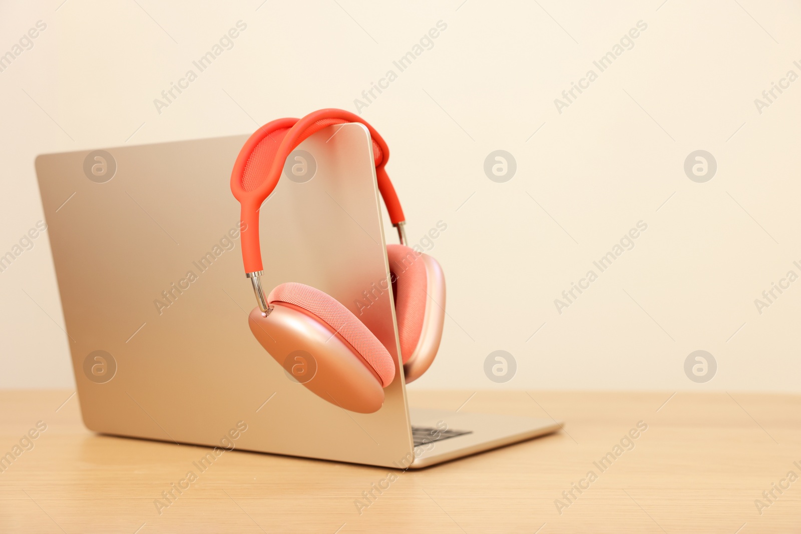 Photo of Modern laptop and headphones on wooden table. Space for text