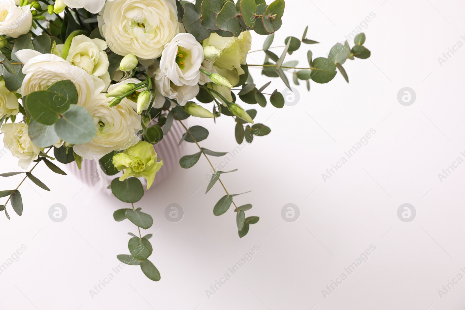 Photo of Vase with beautiful bouquet on white table, above view. Stylish interior element