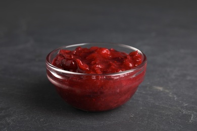 Photo of Bowl of cranberry sauce on grey background, closeup