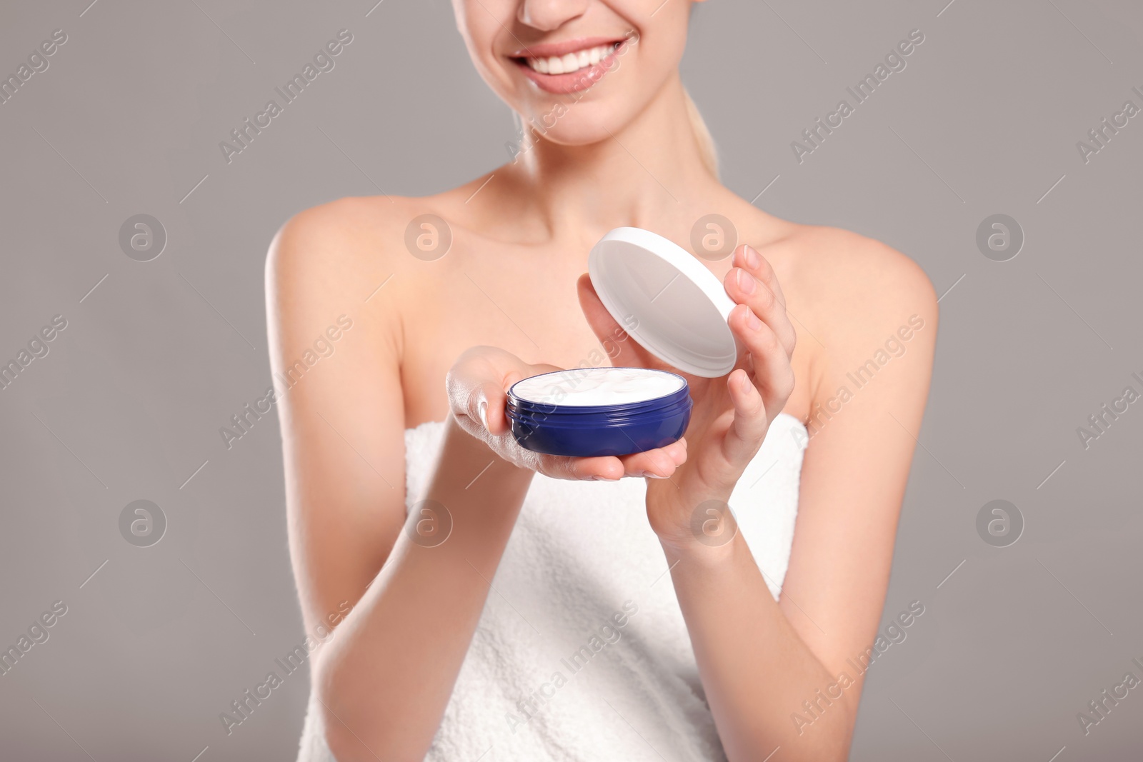 Photo of Young woman with jar of body cream on color background