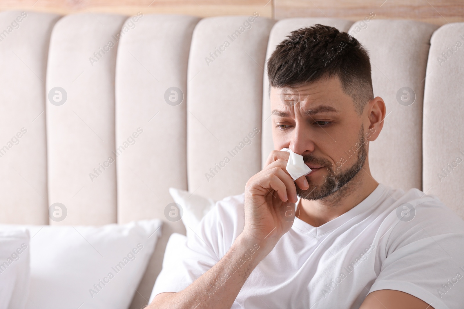 Photo of Man suffering from runny nose in bed. Space for text