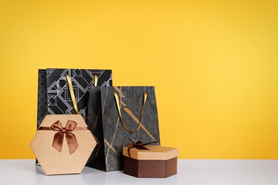 Photo of Shopping bags and gift boxes on yellow background. Space for text