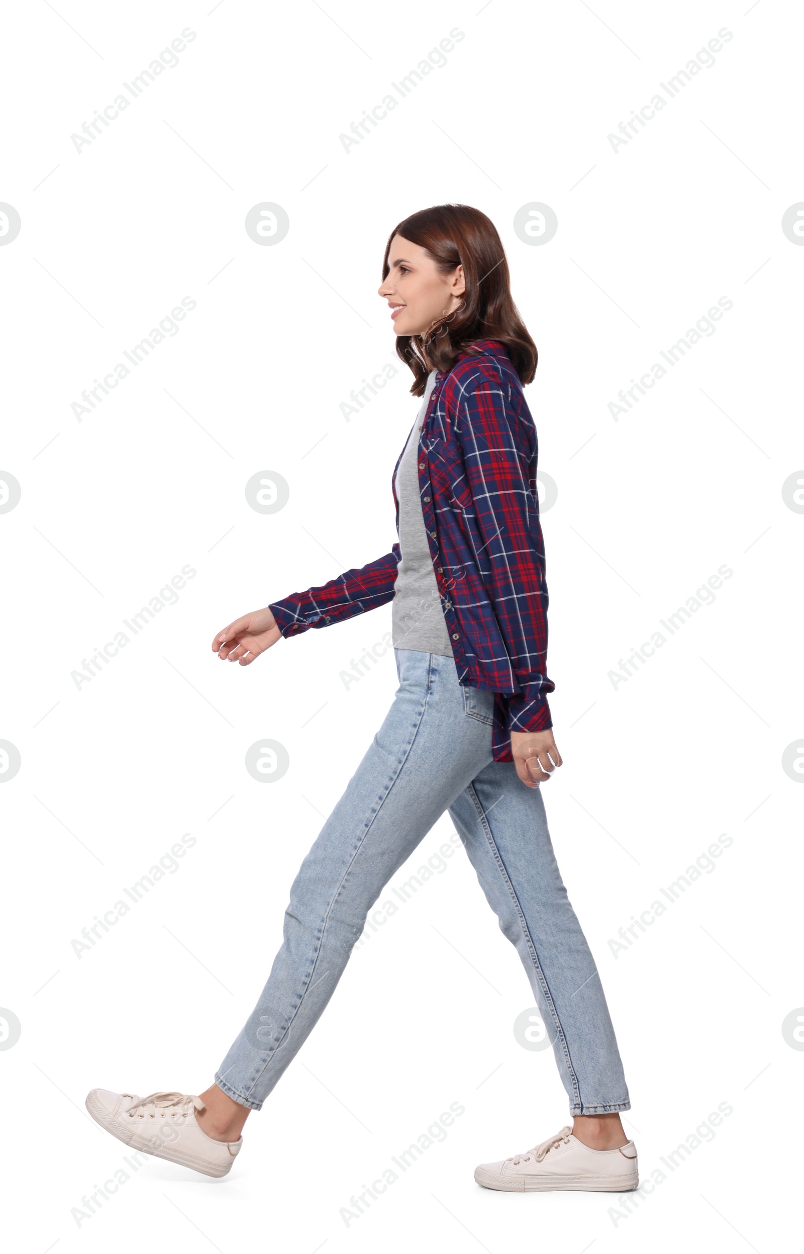 Photo of Beautiful young woman in casual outfit walking on white background